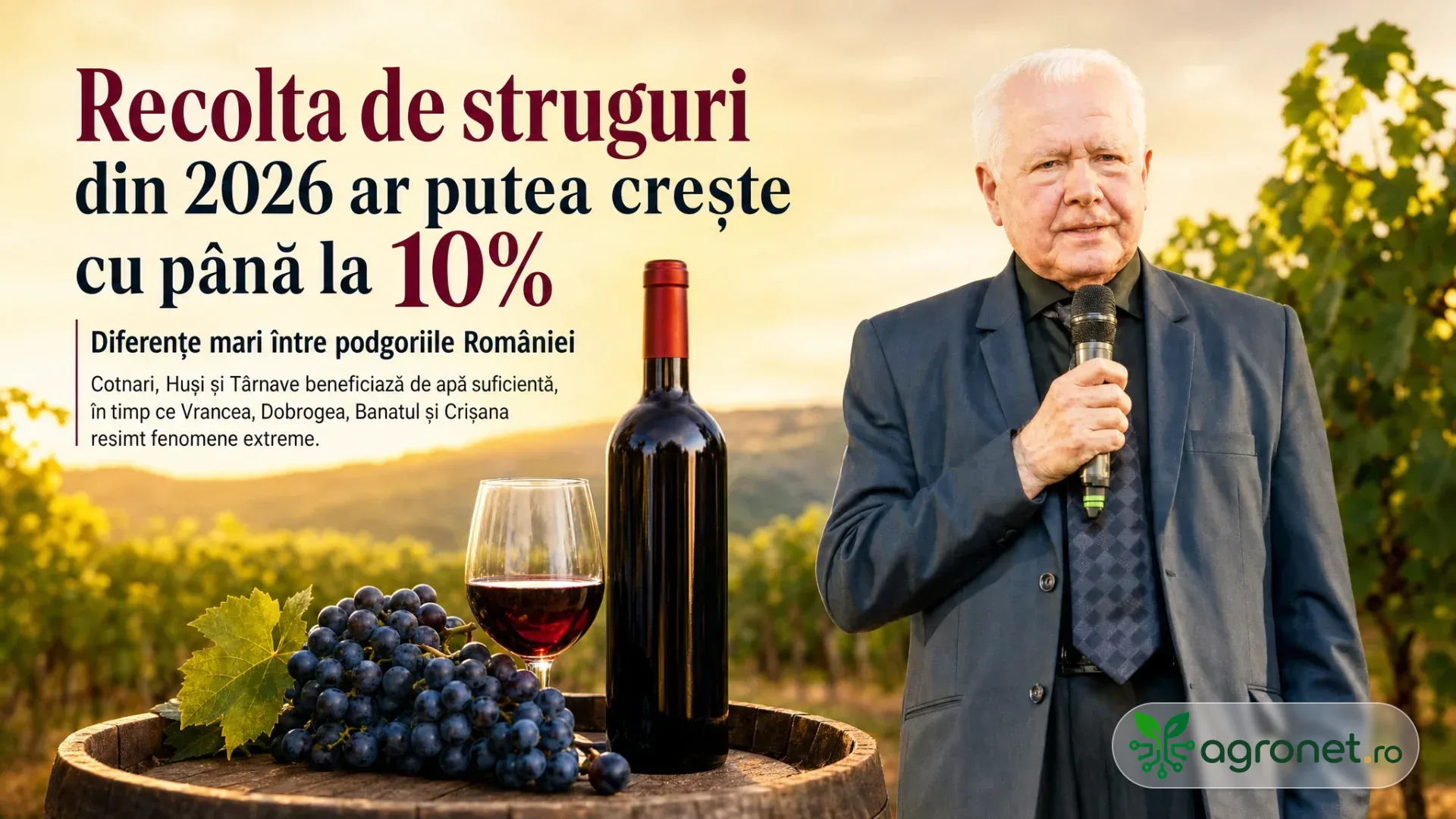 Bărbat cu microfon lângă o masă cu struguri negri, pahar de vin și sticlă, pe fundal de vie.