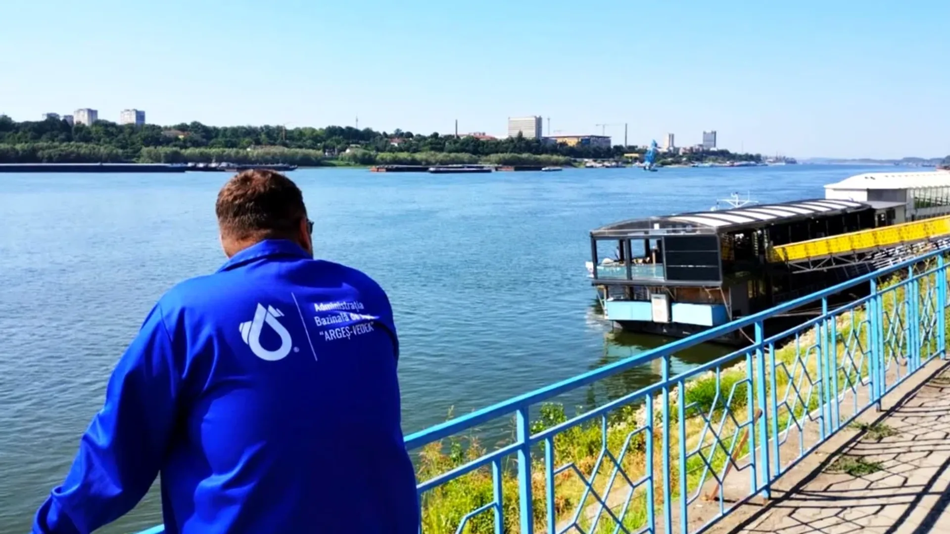 Bărbat în jachetă albastră privind Dunărea de pe promenadă