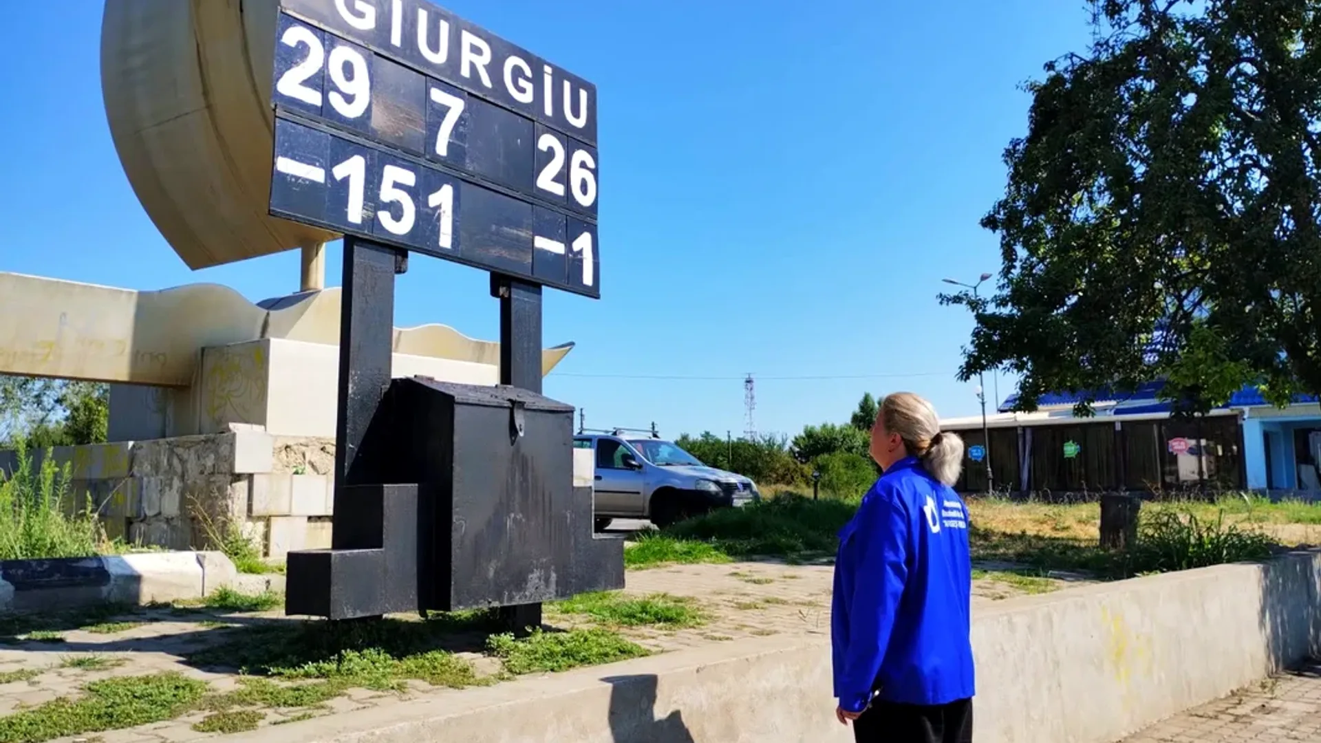 Persoană în uniformă albastră privește un panou hidrometric exterior