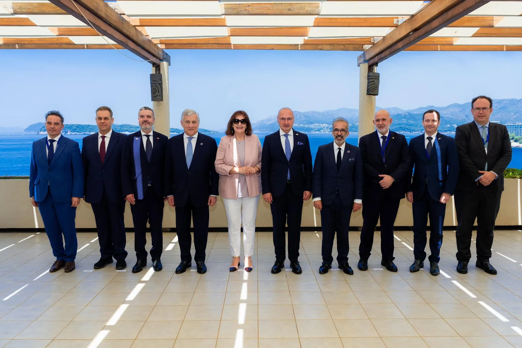 Oficiali în costume pozează pe o terasă, cu marea în fundal