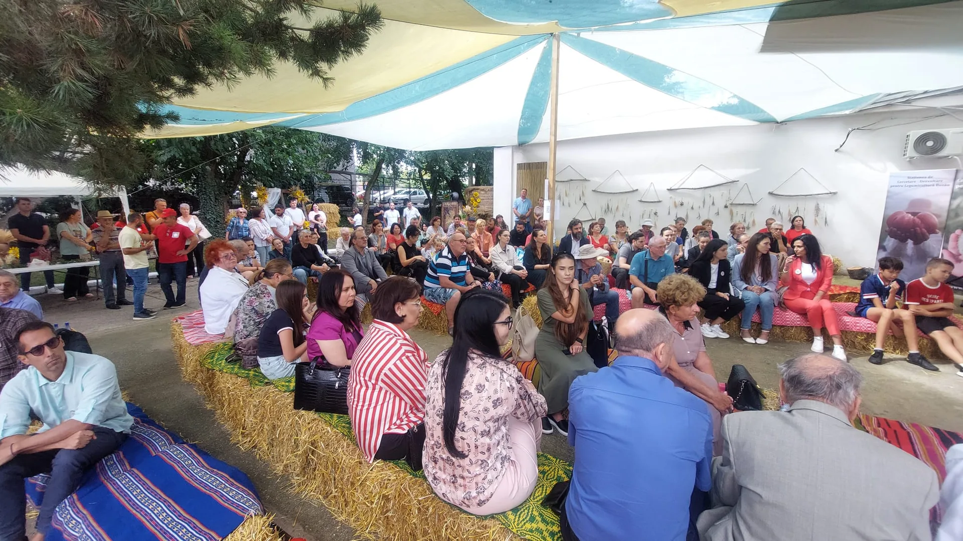 Participanți așezați pe baloți de paie la un eveniment în aer liber