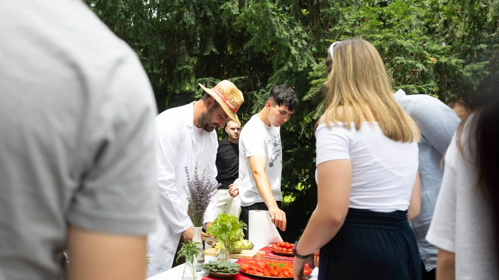 Participanți examinează tomate pe o masă, în aer liber