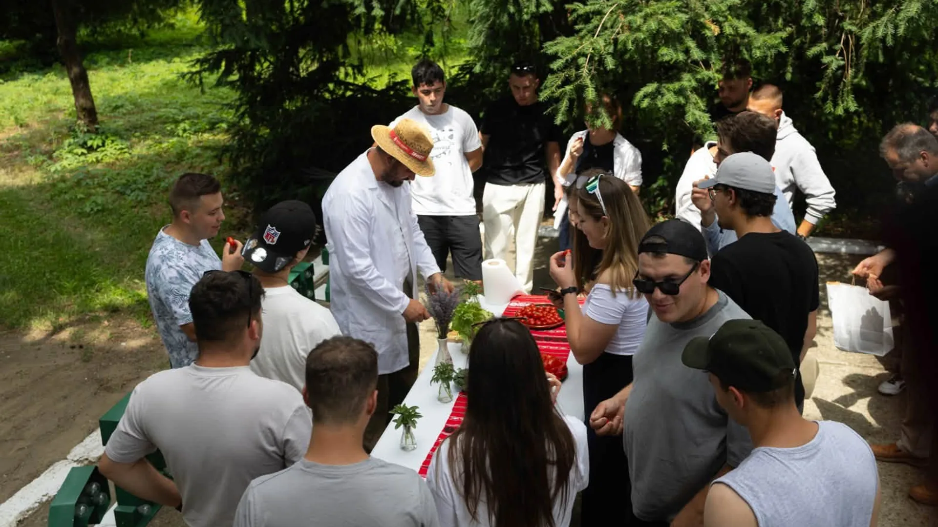 Participanți adunați în jurul mesei cu tomate pentru degustare