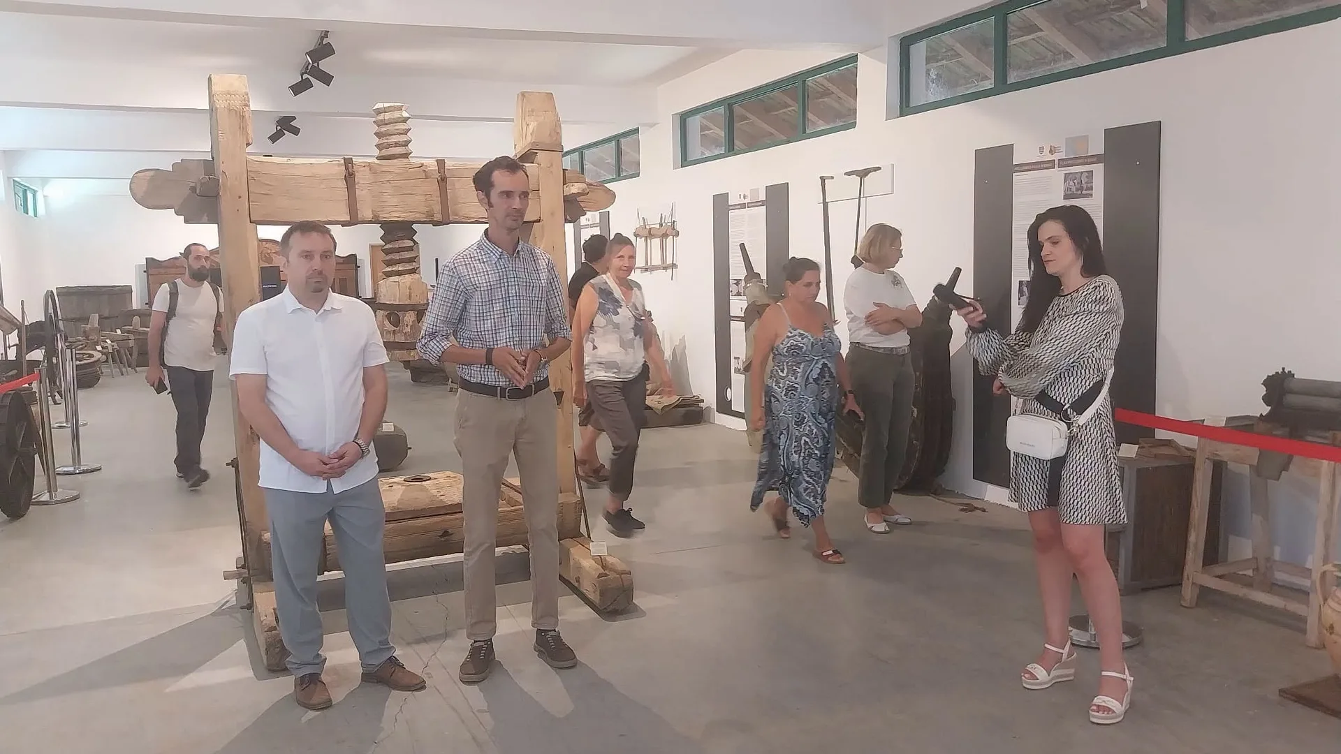 Vizitatori într-o sală de muzeu cu unelte agricole vechi