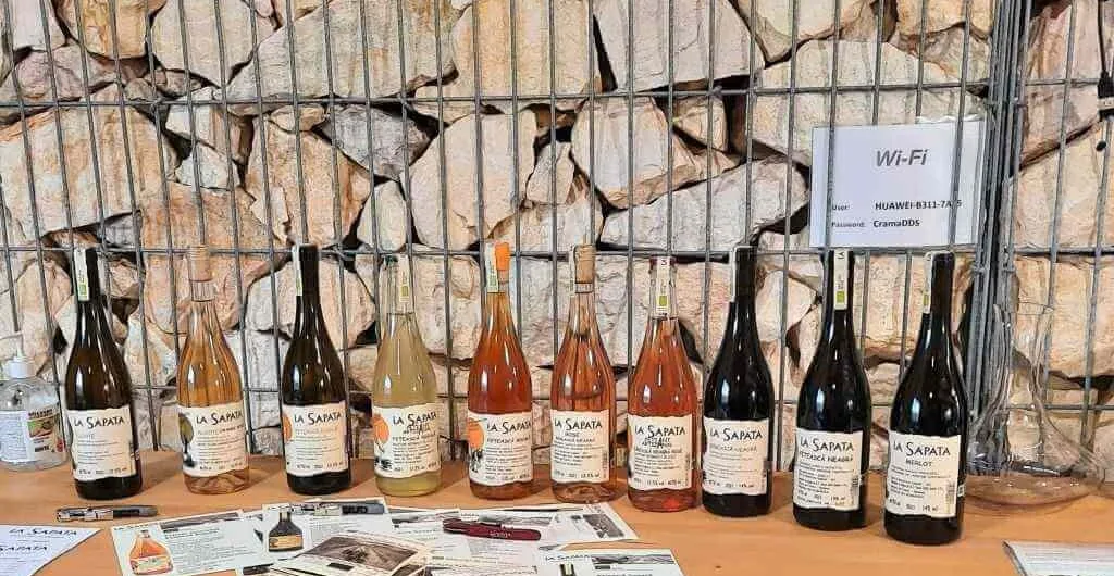 Sticle de vin La Sapata expuse pe masă, lângă un perete din piatră