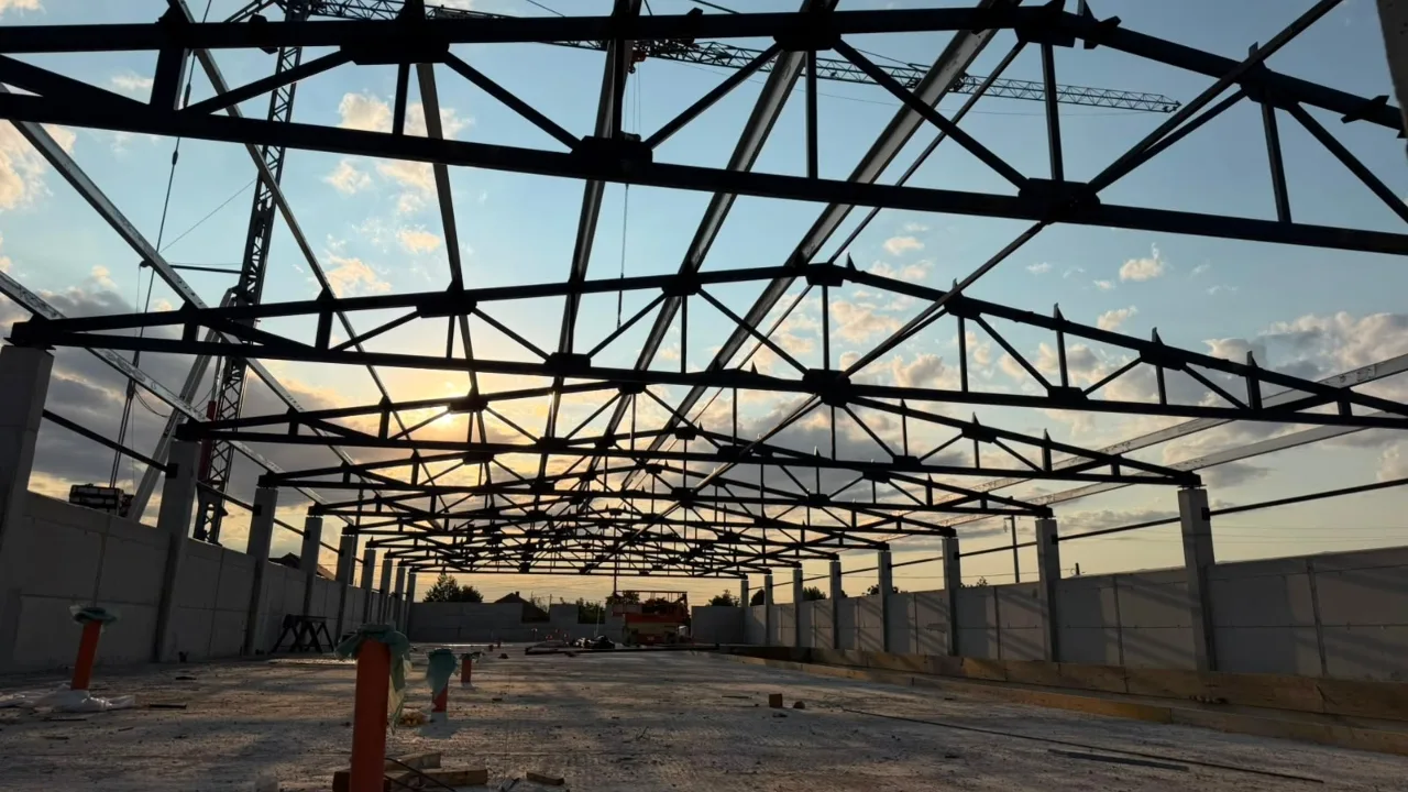 Structură metalică de hală, văzută din interior la apus