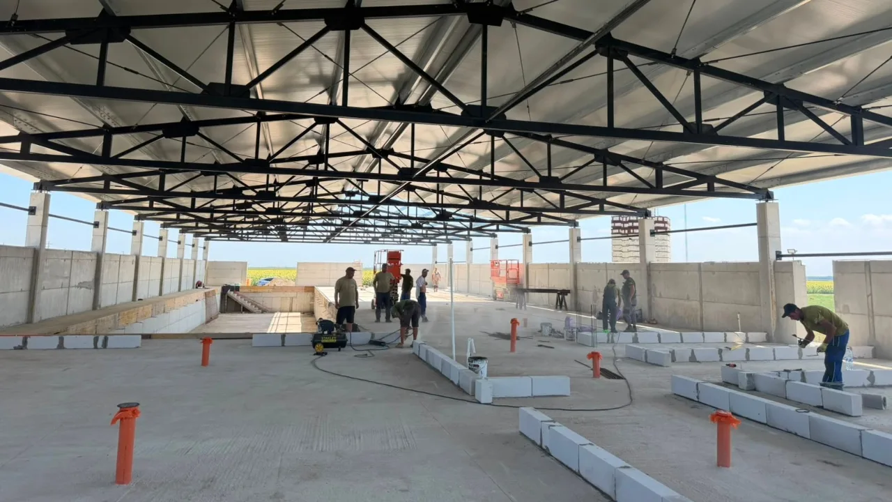 Muncitori montează elemente de beton în interiorul unei hale