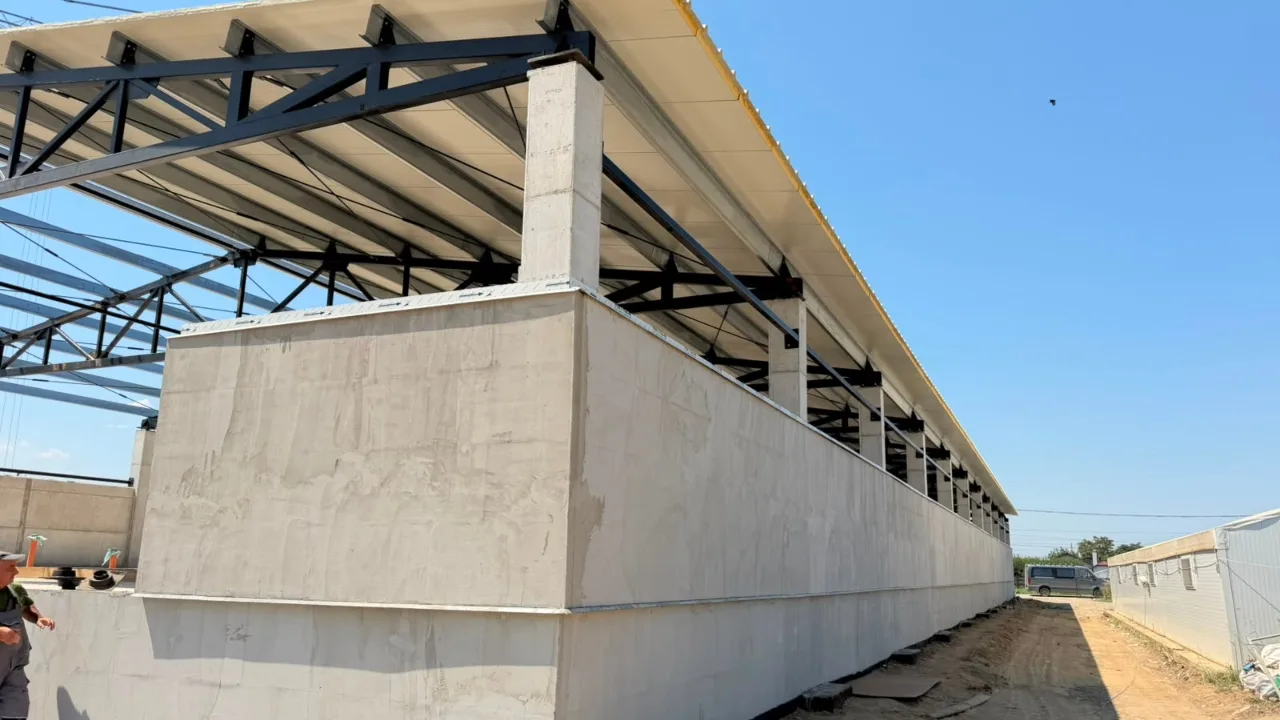 Hală industrială în construcție, cu pereți de beton și acoperiș metalic
