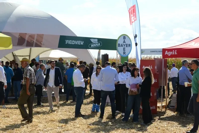 Participanți la summit discută între standuri agricole, pe platforma din câmp