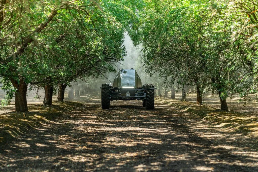 Pulverizator autonom se deplasează printre rânduri de pomi, dispersând ceață fină
