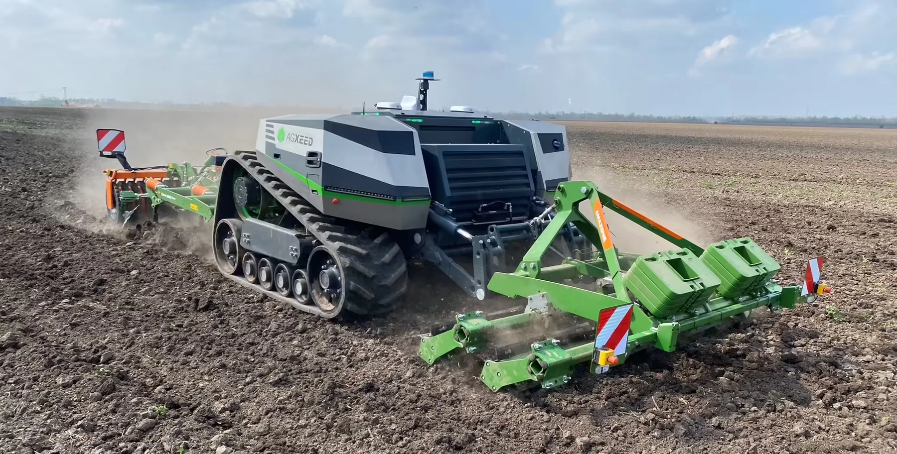 Tractor autonom AgXeed pe șenile lucrează solul cu un utilaj verde